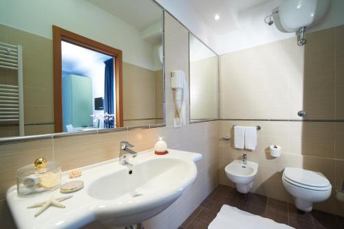 a bathroom with a sink and a toilet and a mirror at Hotel Sirio in Lido di Camaiore