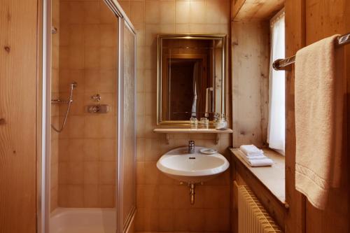 a bathroom with a sink and a shower at Berghotel Ladinia in Corvara in Badia