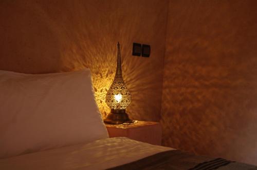 a lamp sitting on a night stand next to a bed at Kasbah La Cigogne in Aït Ben Haddou