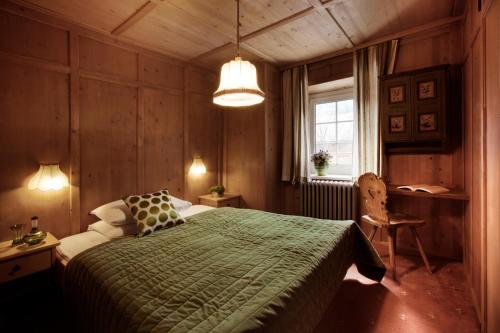 a bedroom with a bed with a green blanket at Berghotel Ladinia in Corvara in Badia