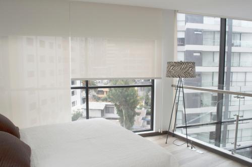 a bedroom with a white bed and a large window at ESPECTACULAR LOFT in Quito