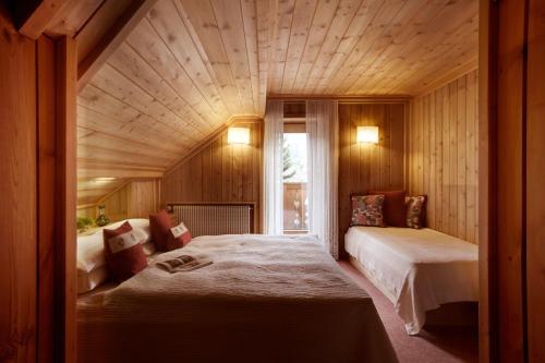 a bedroom with two beds and a large wooden ceiling at Berghotel Ladinia in Corvara in Badia