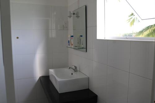 a white bathroom with a sink and a window at Manel Guest House in Polonnaruwa