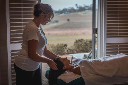 a woman standing next to a woman laying on a bed at The Louise in Marananga