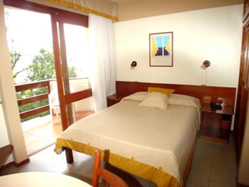 a bedroom with a bed and a balcony at Gramado Serrano in Gramado