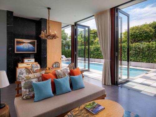 a living room with a couch and a pool at SO/ Sofitel Hua Hin in Cha Am