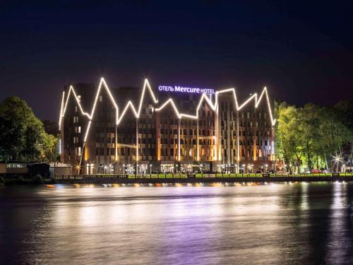 a large building with lights on the water at night at Mercure Kaliningrad in Kaliningrad