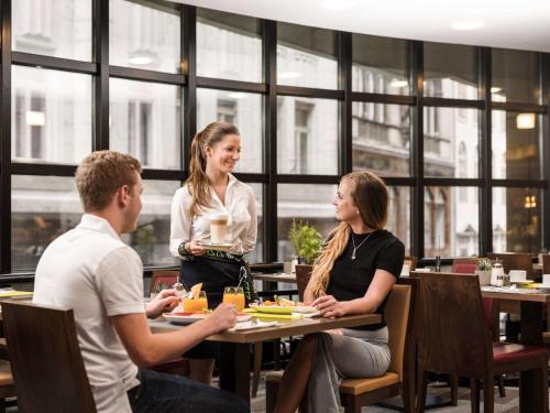 a group of people sitting at a table in a restaurant at Mercure Budapest City Center in Budapest