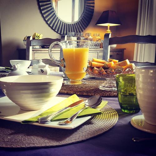 una mesa con un plato de comida y un vaso de jugo de naranja en Chateauret, en Espagnac