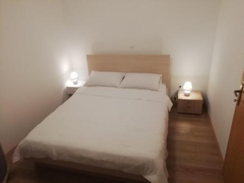a bedroom with a white bed with two lights on it at Ana in Sveti Filip i Jakov