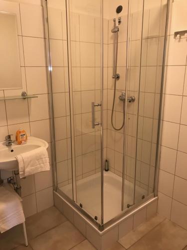 um chuveiro com uma porta de vidro ao lado de um lavatório em City Inn em Berlim