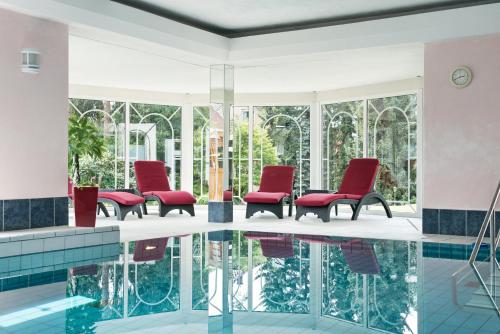 a lobby with red chairs and a pool at Hotel Pieper-Kersten in Bad Laer
