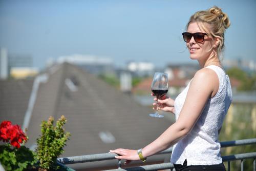 a woman holding a glass of wine on a balcony at HOTEL Am Spichernplatz in Düsseldorf