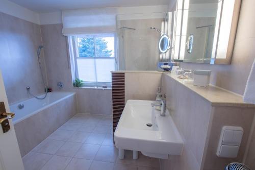 a white bathroom with a sink and a tub and a sink at Romantik Hotel Namenlos in Ahrenshoop