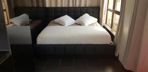 a bedroom with a bed with white sheets and a window at Black loft in Cap d'Agde