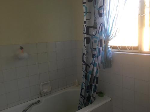 Un baño con bañera y cortina de ducha. en Go Slow, en Port Shepstone