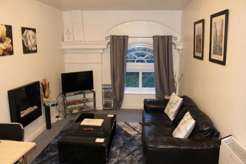a living room with a black leather couch and a window at Victoria Bar Apartments Within the City Walls Free Parking in York