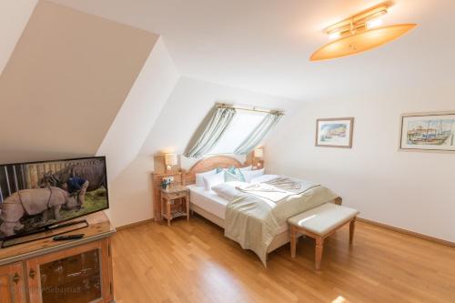 a bedroom with a bed and a flat screen tv at Romantik Hotel Namenlos in Ahrenshoop