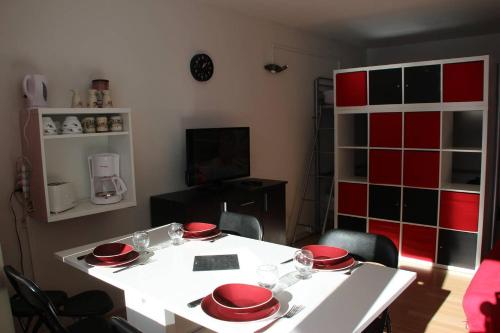einen weißen Tisch mit rotem Geschirr darüber in der Unterkunft Studio au pied des pistes + Cellier in La Mongie