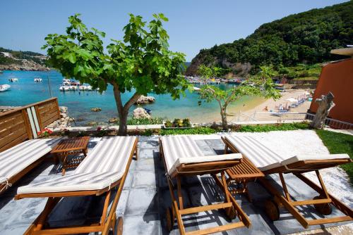 a group of chairs and tables and a beach at Tango Apartment On The Beach in Paleokastritsa