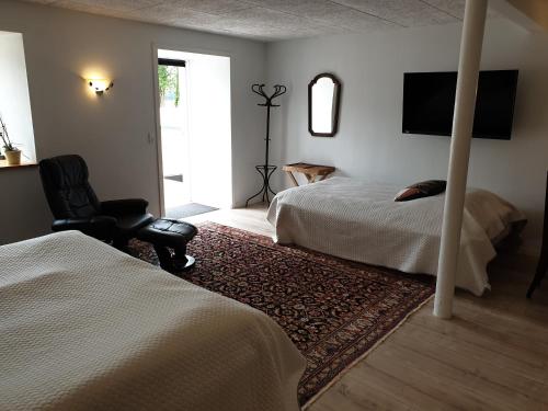 a bedroom with two beds and a chair and a television at Gørdinglund Herregård Bed & Breakfast in Gørding