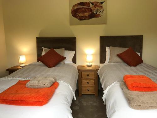 two beds in a bedroom with orange towels on them at Moelfre B&B in Machynlleth