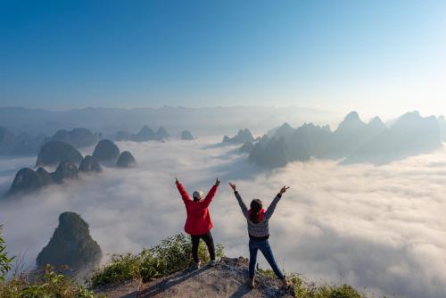 two people standing on top of a mountain with their hands up at Secret Courtyard Resort Hotel in Guilin