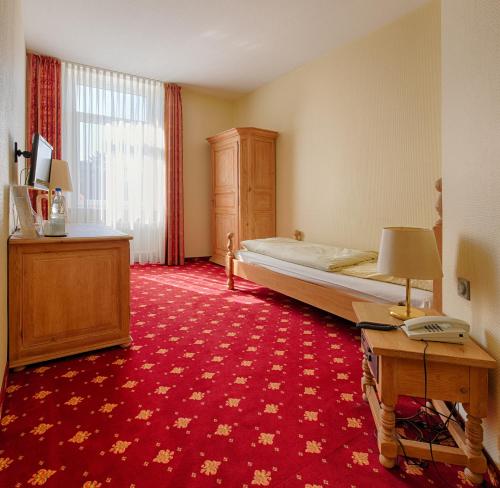 a hotel room with a bed and a desk and a table sidx sidx at Hotel Kronprinz Garni in Minden
