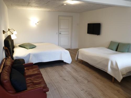 a room with two beds and a couch and a tv at Gørdinglund Herregård Bed & Breakfast in Gørding
