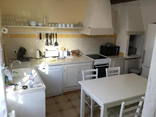 a kitchen with white appliances and a white table and chairs at Aux pieds des arènes in Arles