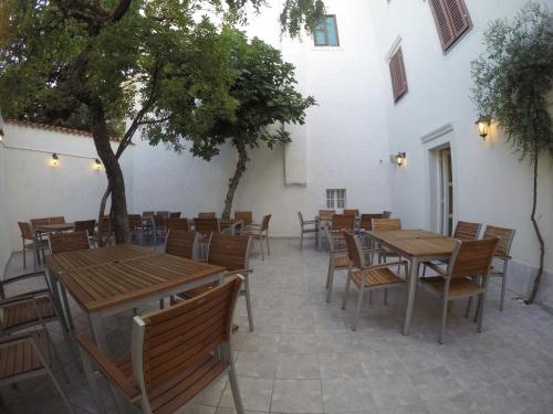 un patio con mesas y sillas de madera y un árbol en Guest House Neho, en Cres