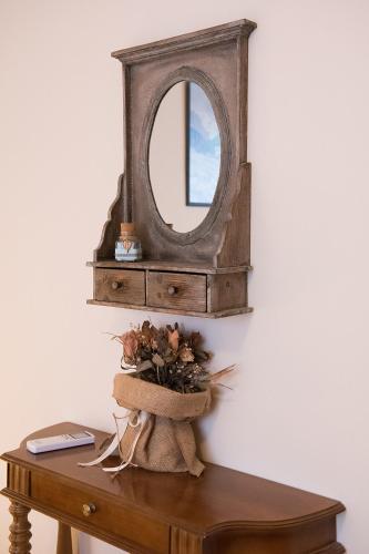 a mirror on a wall next to a table with a vase at Agrelia in Agreliá