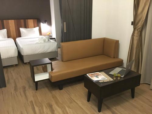 a hotel room with a couch and a bed and a table at The Museum Hotel in Nakhon Pathom