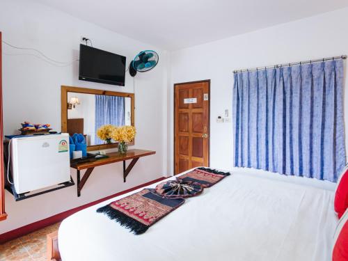 a bedroom with a bed and a television and a table at Rendezvous Oldtown Chiangmai in Chiang Mai