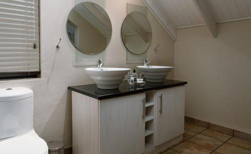 a bathroom with two sinks and two mirrors at ADamsview in Gariepdam