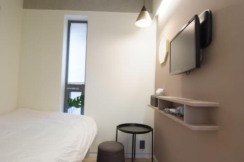 a bedroom with a bed and a flat screen tv on the wall at DW STAY HONGDAE in Seoul