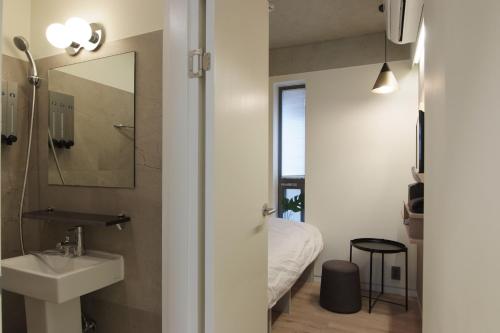 a bathroom with a sink and a mirror and a bed at DW STAY HONGDAE in Seoul