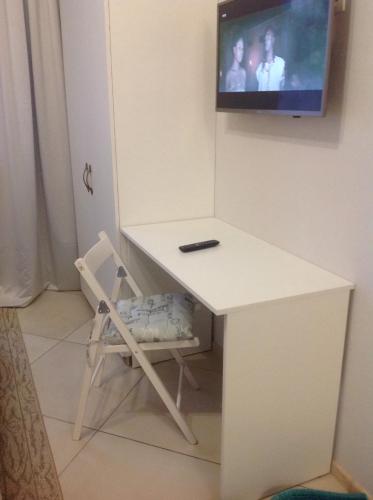 a white desk with a chair and a tv on a wall at Дом in Kyiv