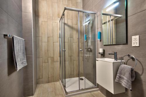 a bathroom with a shower with a sink and a mirror at Cozy Rooms Hotel in Sliema