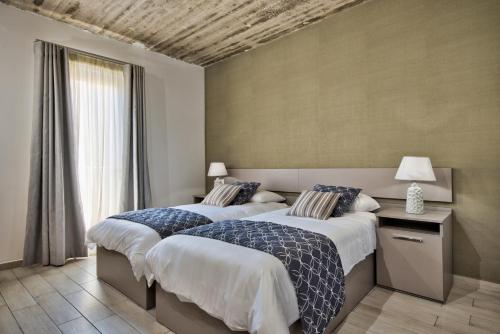 a bedroom with two beds and a window at Cozy Rooms Hotel in Sliema