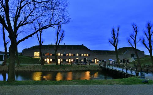 a large building with a bridge in front of a river at Bed & Breakfast Fort Bakkerskil in Nieuwendijk