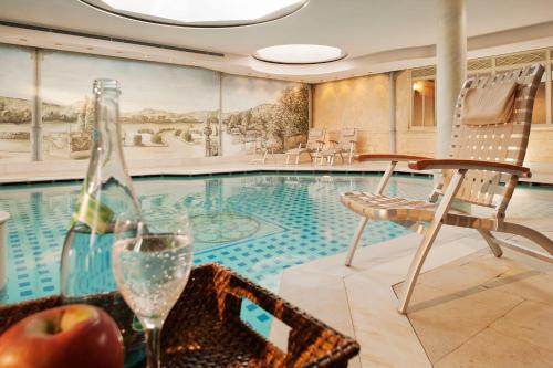 a bottle of wine and an apple on a table next to a swimming pool at Hotel Aarnhoog in Keitum