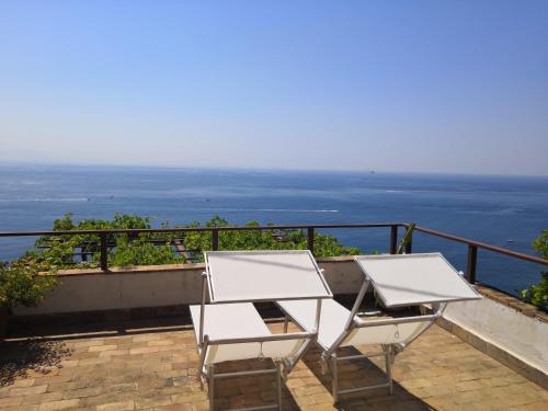 2 sillas blancas sentadas en un balcón con vistas al océano en Il Nido del Gabbiano, en Vietri