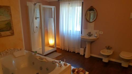a bathroom with a tub and a toilet and a sink at B&B Villa Fiorini in Moniga