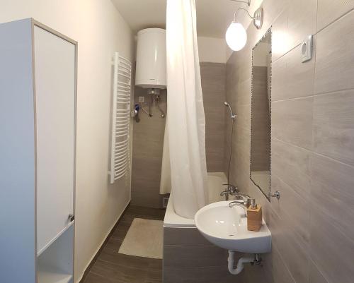 a white bathroom with a sink and a shower at Hóvirág Apartman Balatonberény in Balatonberény