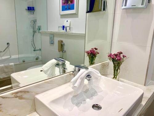 een badkamer met een witte wastafel en een spiegel bij Gulf Inn Hotel Al Nasr Formerly Roda Links Al Nasr in Dubai