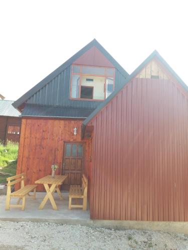 a red building with a picnic table and a house at Guest House Vukicevic in Žabljak