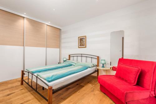 um quarto com uma cama e uma cadeira vermelha em Apartments Linda em Sestrunj