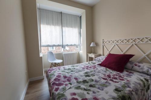 a bedroom with a bed with a floral bedspread and a window at Acogedor Apartamento en Santander in Santander