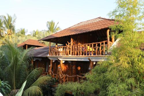 a wooden house with a deck in the trees at Sayang Mama Inn in Gili Air